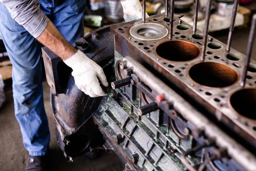 Mechanic repairs old motor of truck in a car repair station. Disassemble engine block vehicle. Motor capital repair. Car service concept